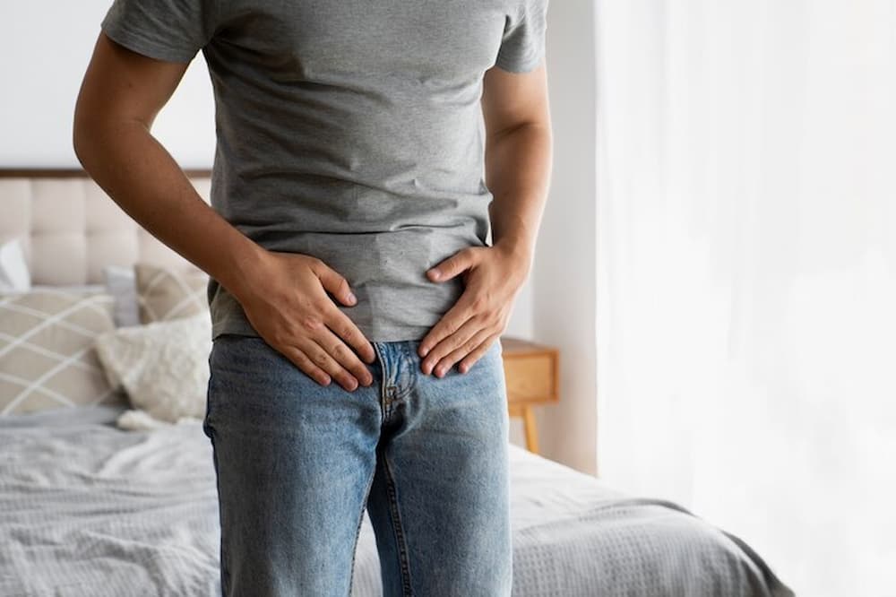 Hombre tocando su pelvis con ambas manos