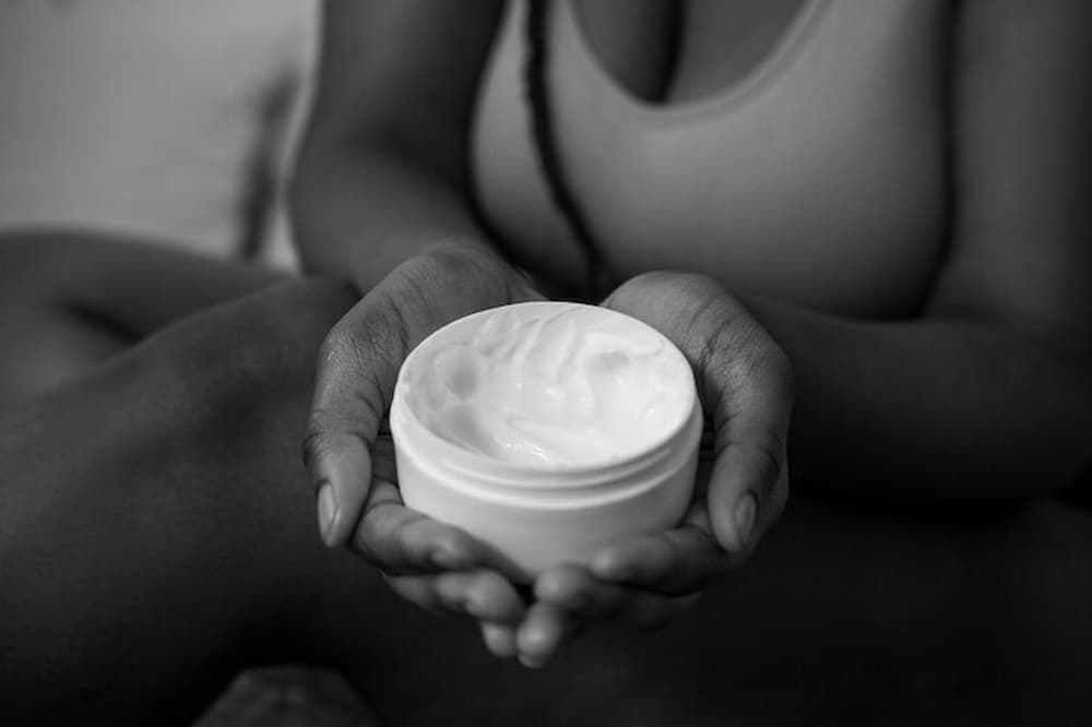 Mujer sosteniendo tarro de crema retardante
