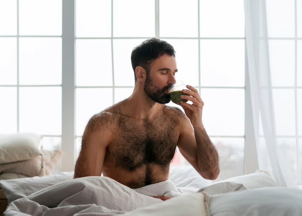 Hombre en la cama tomando bebida